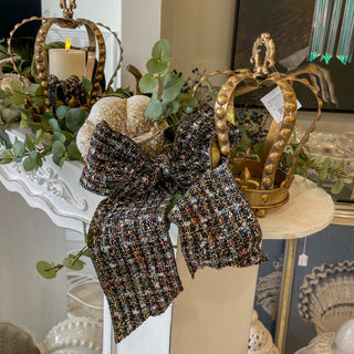 Decorative headband with plaid design surrounded by greenery and a candle.