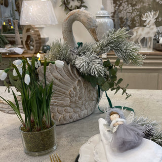 Decorative swan with floral arrangement on a table with a blurred background