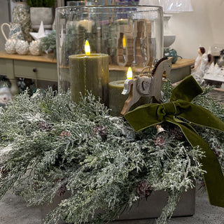 Collette’s Winter Hurricane Glass Centre with greenery, sage LED candle and green velvet bow. Buy online at www.lilybloom.ie.”