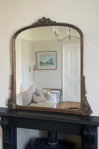 An antique brass overmantle mirror from www.lilybloom.ie set over a black fireplace
