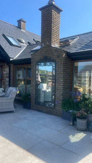 Tivoli Ornate Distressed Mirror hung on a brick exterior wall with a distressed corten-style iron frame. Ideal for patios, outdoor feature walls, courtyards and garden rooms. Shop online at Lily Bloom, Gorey, Co. Wexford.