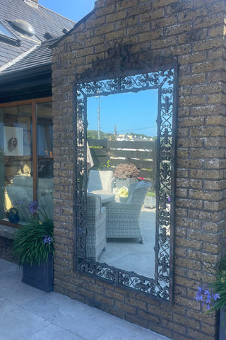 Tivoli Ornate Distressed Mirror with an aged corten-style iron frame. Oversized statement mirror fitted on an external brick wall.  Available at Lily Bloom, Gorey, Ireland.