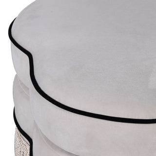 Side profile of curved white ottoman with black tassel detailing