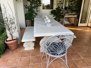 Outdoor dining area with a white table and chairs on a tiled patio.